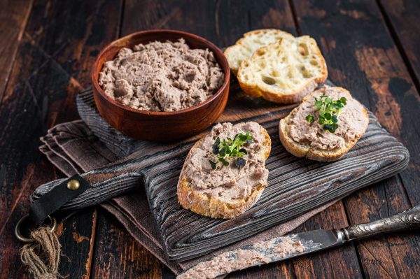 Toasts with Duck pate Rillettes de Canard on wooden board. Dark